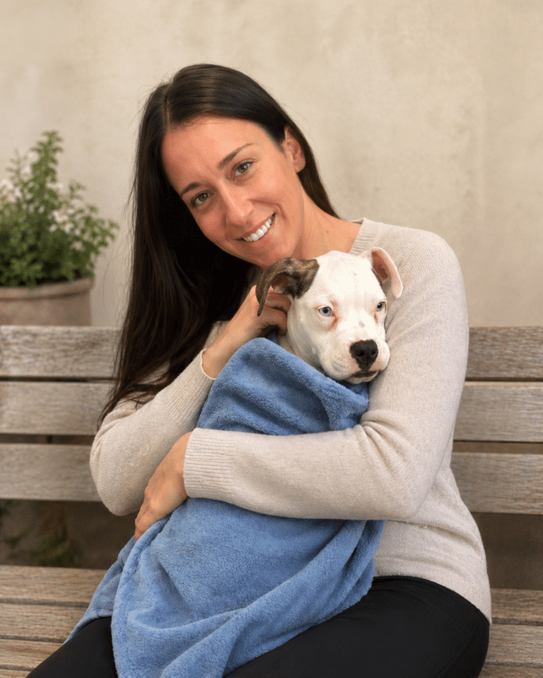 Photo of Michelle holding a dog wrapped in a blanket